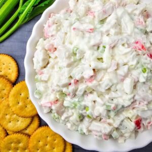 Crab salad in white dish with celery and crackers.