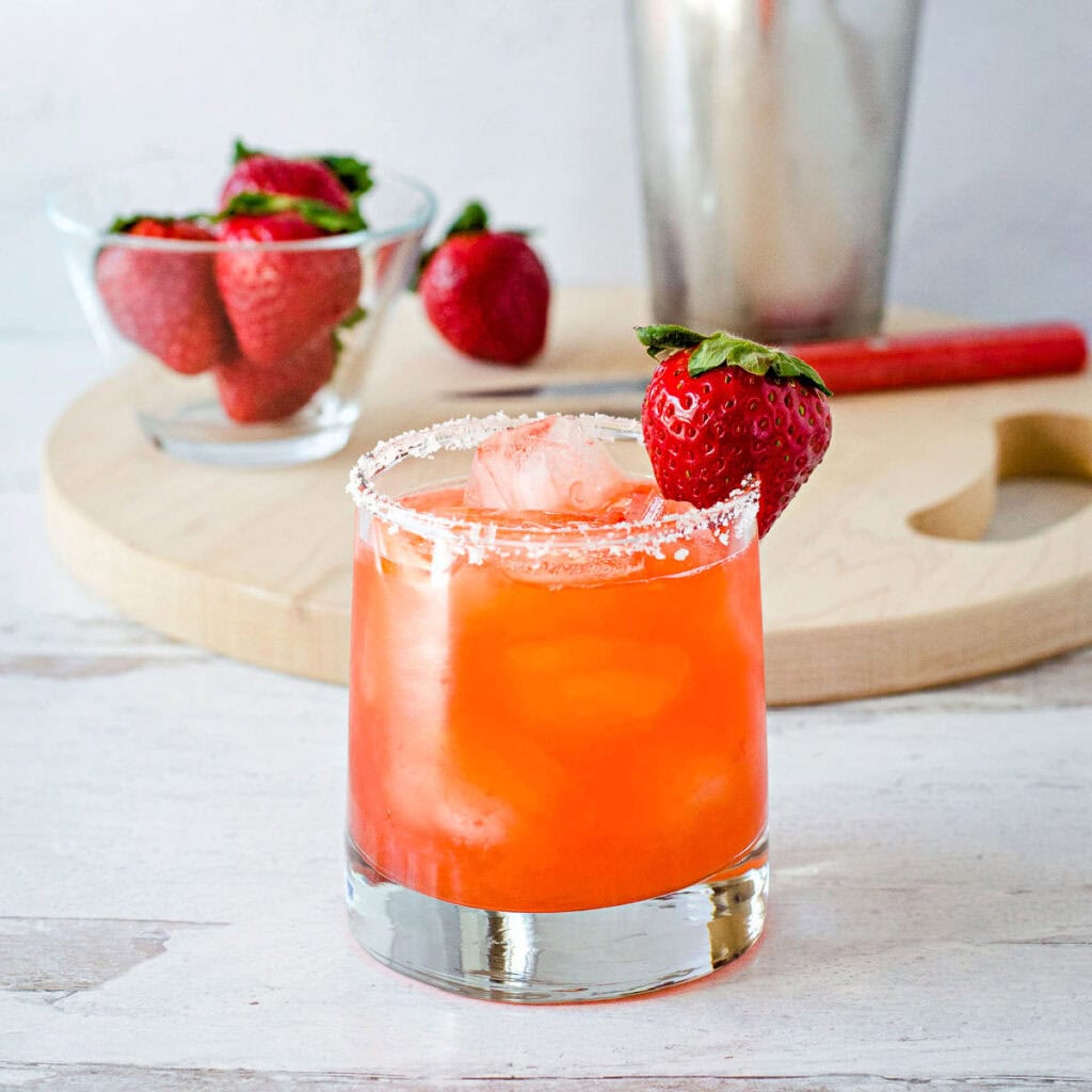Strawberry margarita with strawberries on cutting board.