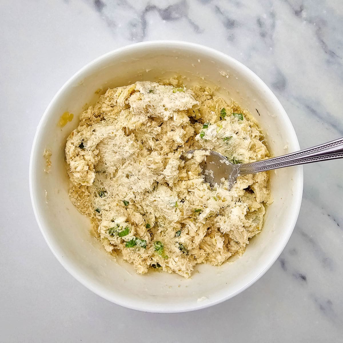 Stuffing mixture in a white bowl with a spoon.