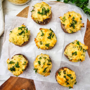 Crab stuffed mushrooms with melted cheese on top on a board.