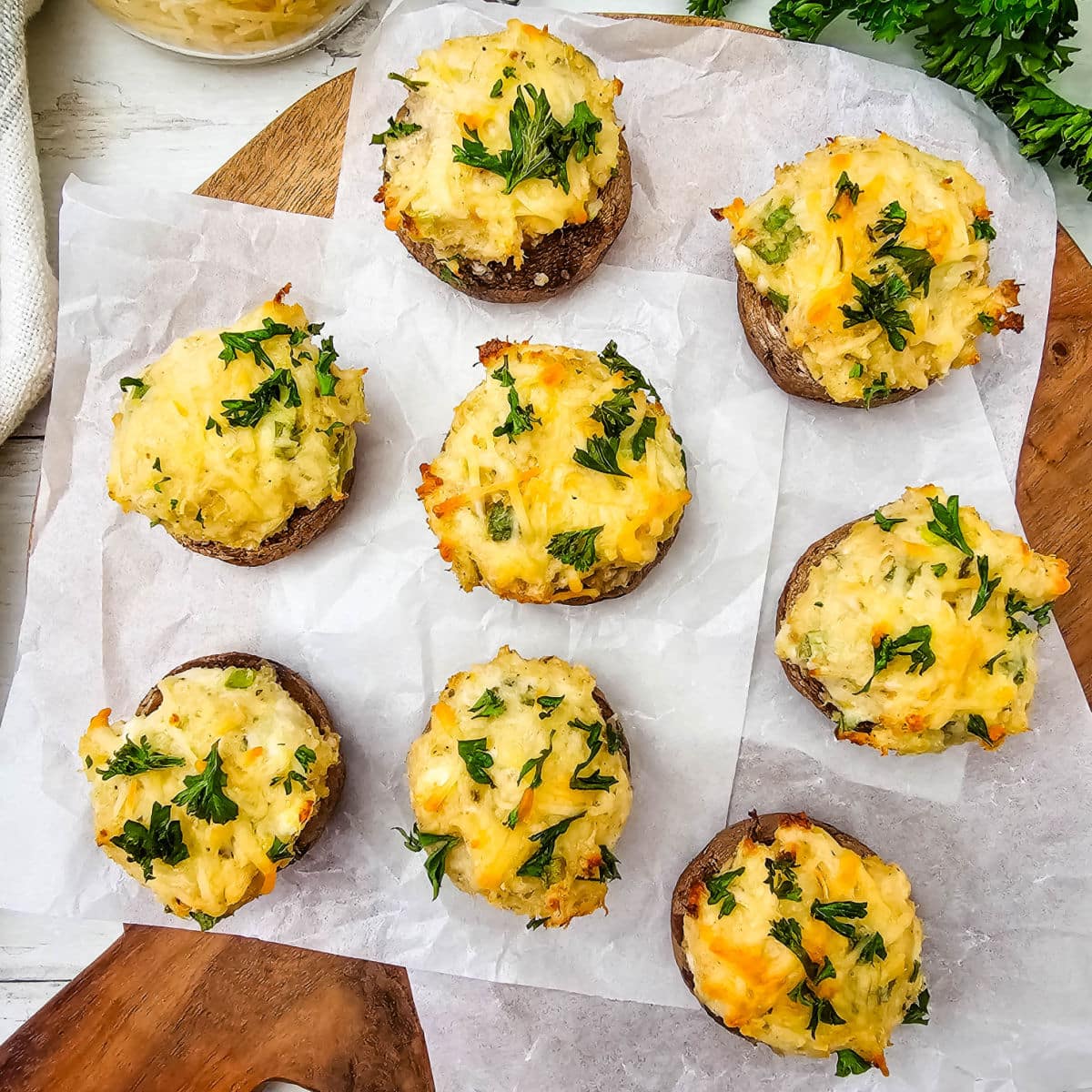 Crab stuffed mushrooms with melted cheese on top on a board.
