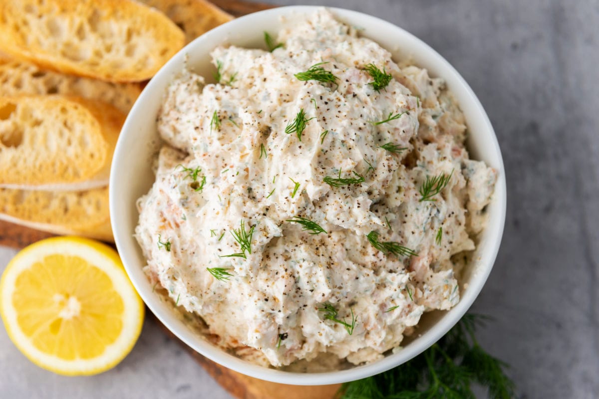 Bowl of smoked salmon dip with toast and lemon half.